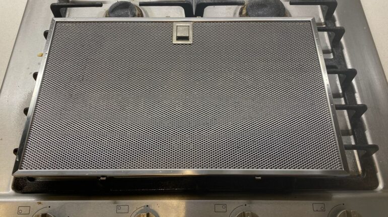 Metallic range hood filter on stove